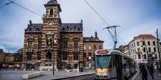 Scène de rue à Anderlecht avec un plombier effectuant un débouchage de canalisation, architecture typique en arrière-plan.