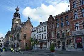 Scène urbaine de Binche avec un artisan de débouchage, rues pavées et architecture typique. Débouchage Binche en action.