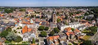 Scène urbaine avec camion Débouchage Braine-l'Alleud devant l'église Saint-Étienne et son clocher emblématique.