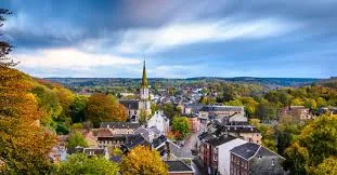 Scène urbaine à Eupen montrant le service de débouchage dans une rue typique avec ses maisons en briques et son église.